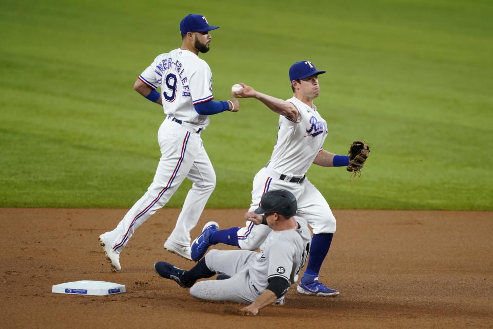 Texas Rangers shortstop Isiah Kiner-Falefa, left, looks on as second baseman Nick Solak, right, throws to first after forcing New York Yankees' Brett Gardner, center, at second to complete the double play against Aaron Judge in the first inning of a baseball game in Arlington, Texas, Tuesday, May 18, 2021. (AP Photo/Tony Gutierrez)