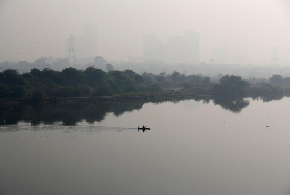 <p>A man rows a boat as buildings shrouded in smog are seen in the background on the outskirts of Delhi, India, November 15, 2021. REUTERS/Adnan Abidi</p> 