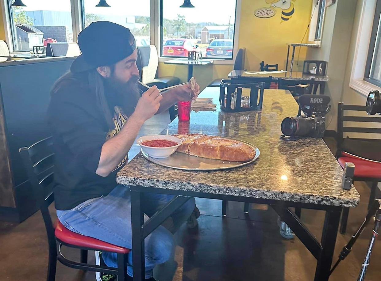 Competitive eater and YouTube star Adam Moran from England is pictured Jan. 4 as he tackles the calzone challenge at Tre Ragazzi's Glencoe location. It involves eating the restaurant's super-sized calzone with at least three toppings, including two meats, within an hour.