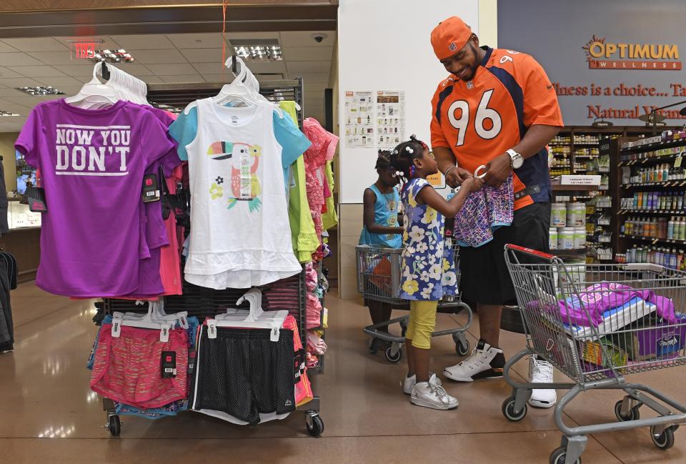 <p>Denver Broncos defensive end Vance Walker, #96 helps Brooklyn Hill, 6, in floral, pick out some clothes as they shop at King Soopers Marketplace on July 25, 2016 in Parker, Colorado. Behind them is Gabriella Asamoah, 6. </p>