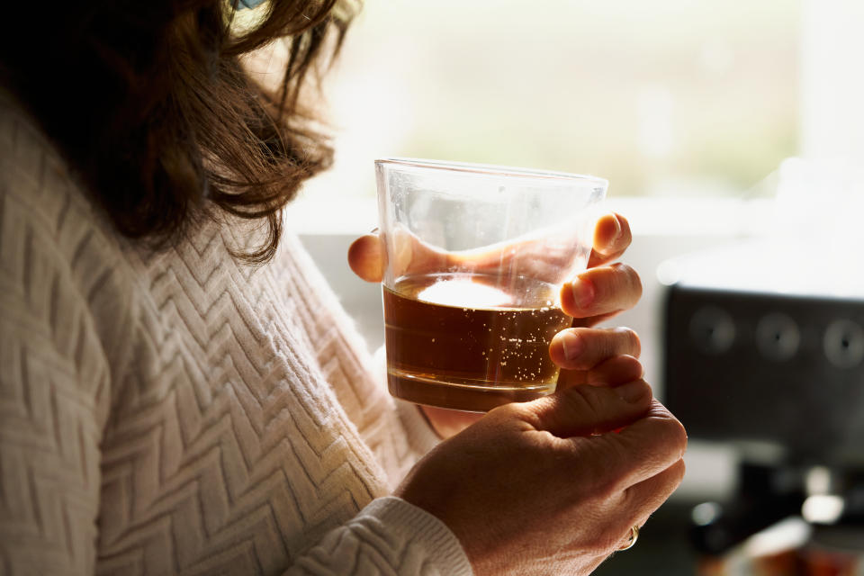 glass cup between hands woman with a glass of alcohol in her hands in front of a window