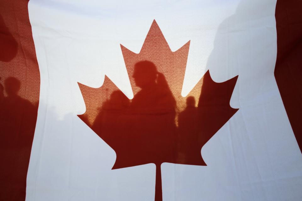 Israelis are silhouetted behind a Canadian flag at a rally to thank Canada's Prime Minister Stephen Harper for his support of Israel during his visit at the Israeli parliament in Jerusalem January 20, 2014. REUTERS/Ammar Awad (JERUSALEM - Tags: POLITICS)