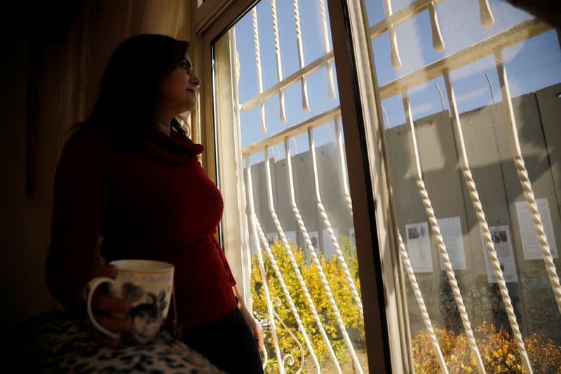 A Palestinian Christian woman looks through the window of her home that is adjacent to the Israeli wall, in Bethlehem the Israeli-occupied West Bank