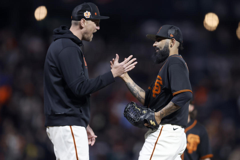 San Francisco Giants pitcher Sergio Romo, right, is removed by former player Hunter Pence, left, during the seventh inning of a spring training baseball game against the Oakland Athletics in San Francisco, Monday, March 27, 2023. (AP Photo/Jed Jacobsohn)