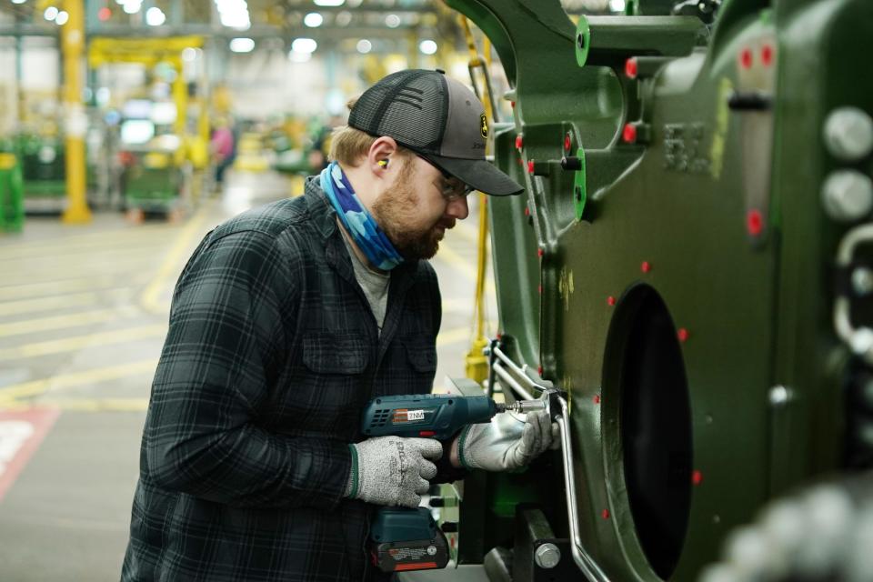 Operator Chris Smith installs a clamp that holds together hydraulic lines on an 8RT tractor chassis.