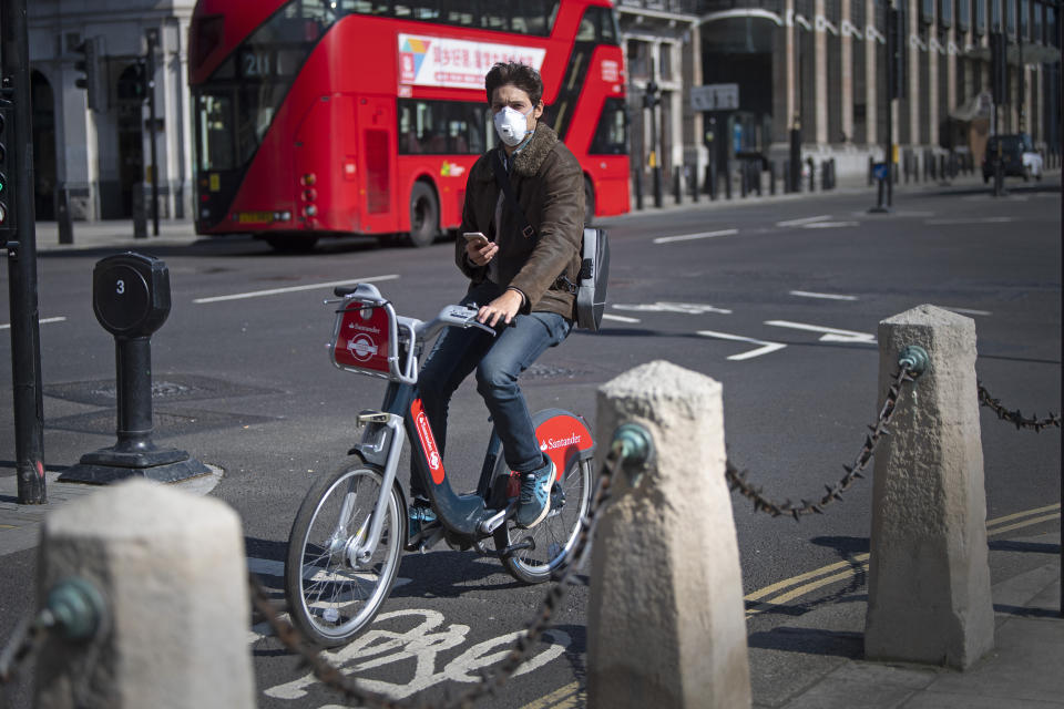 A man wearing a protective face mask cycles in Parliament Square in central London, after Prime Minister Boris Johnson has put the UK in lockdown to help curb the spread of the coronavirus.