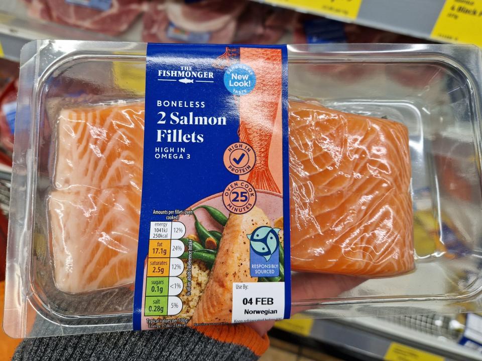 The writer holds a pack of two salmon filets