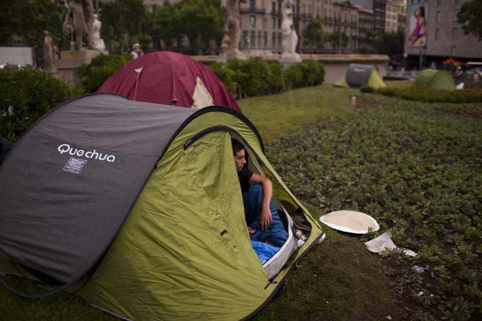 A protester is seen inside his tent as he spends the night at the Catalunya square during a protest to mark the anniversary of the "Indignados" movement in Barcelona, Spain, Sunday May 13, 2012. Spaniards angered by increasingly grim economic prospects and unemployment hitting one out of every four citizens protested in droves Saturday in the nation's largest cities, marking the one-year anniversary of a spontaneous movement that inspired similar anti-authority demonstrations across the planet. (AP Photo/Emilio Morenatti)