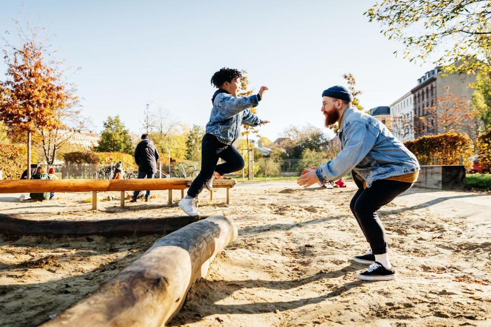 young boy leaping into father arms in playground