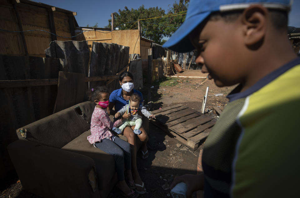 Residents sit outside in the Jardim Julieta squatter camp in Sao Paulo, Brazil, Thursday, July 23, 2020. The coronavirus had just hit the city when this parking lot for trucks became a favela, with dozens of shacks. Since the first wave of residents in mid-March, hundreds of families joined, with most having been evicted during the pandemic. (AP Photo/Andre Penner)