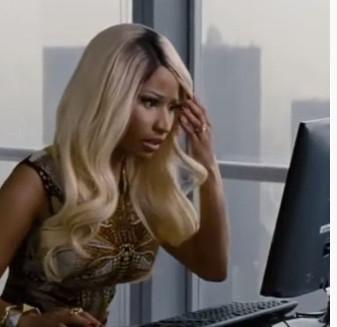 Nicki Minaj reading something closely on a computer in a scene from "The Other Woman