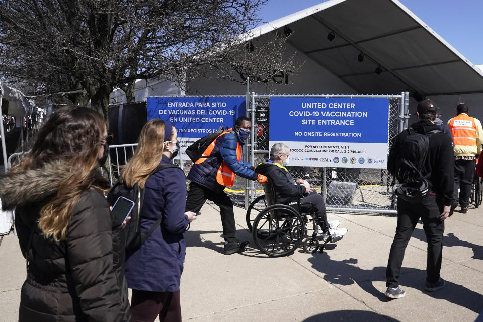 FILE - In this March 29, 2021, file photo, Chicago area residents head into a walk-in mass vaccination site across the street from the United Center, home to the Chicago Bulls and Blackhawks in Chicago. The U.S. moved closer Thursday, April 1, toward vaccinating 100 million Americans in a race against an uptick in COVID-19 cases that is fueling fears of another nationwide surge just as the major league baseball season starts and thousands of fans return to stadiums. (AP Photo/Charles Rex Arbogast, File)