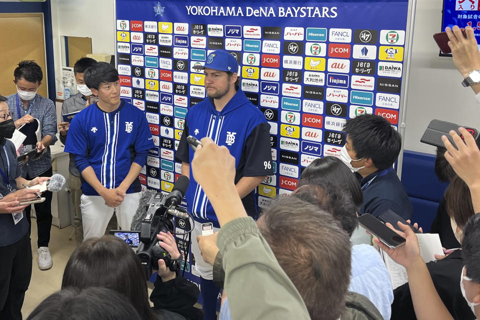 Yokohama DeNA BayStars pitcher Trevor Bauer, center, is surrounded by reporters during a post-game press conference in Yokohama, near Tokyo, Wednesday, May 3, 2023. After cheerleaders welcomed him, after receiving the largest ovation of any Yokohama player at the start of the game, Bauer delivered what was expected on Wednesday in his debut with the Yokohama DeNA Baystars.(AP Photo/Stephen Wade)