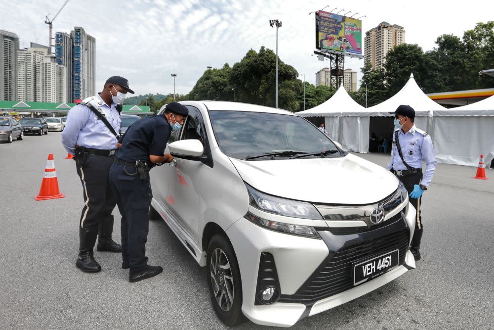 Police personnel conduct checks on vehicles at the Duta toll exit in Kuala Lumpur May 27, 2020. — Picture by Ahmad Zamzahuri