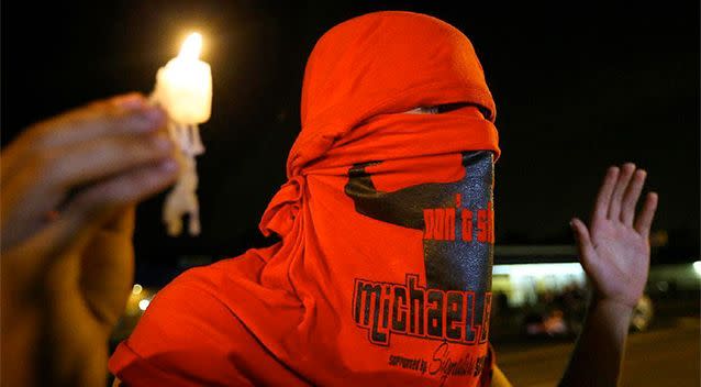 A protester holds a candle while marching silently with his hands up on West Florissant Avenue in Ferguson. Photo: AP