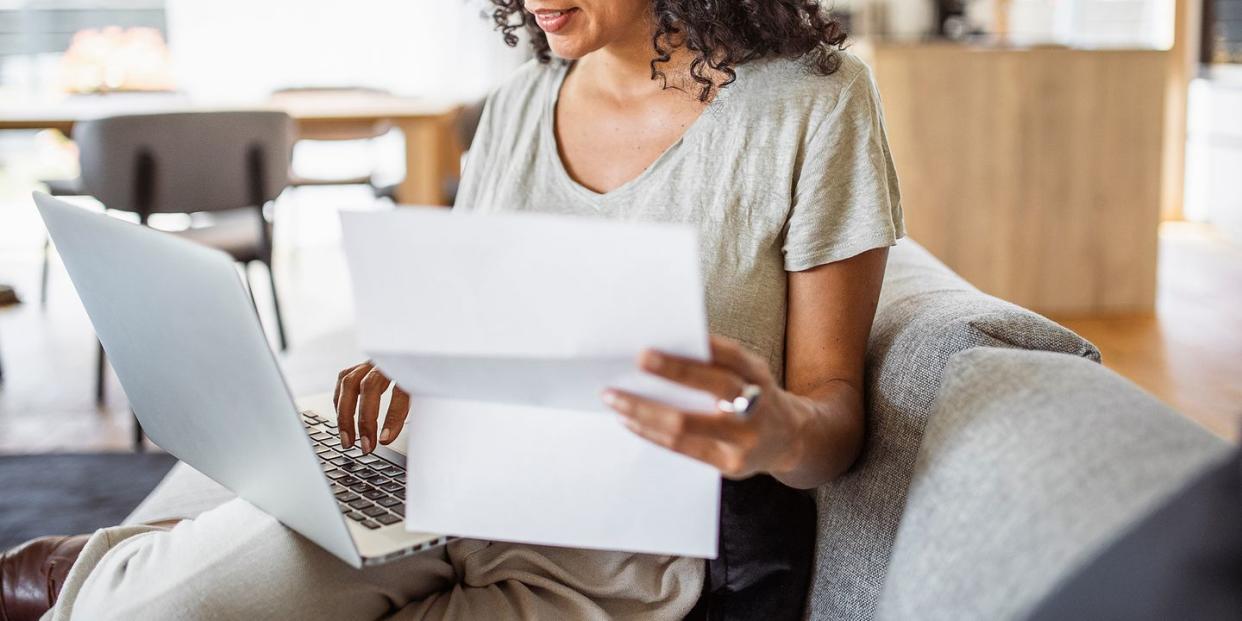 mid adult woman looking at paperwork and laptop