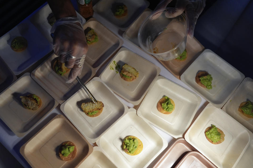 Olga Leon places pieces of "lab-grown" atop guacamole as she serves up cultivated chicken tostadas at a pop-up tasting hosted by California-based producer Upside Foods, Thursday, June 27, 2024, in Miami. As Florida's ban on lab-grown meat is set to go into effect next week, one manufacturer held a tasting party, serving up cultivated chicken tostadas to dozens of attendees on a rooftop in Miami's Wynwood neighborhood. (AP Photo/Rebecca Blackwell)