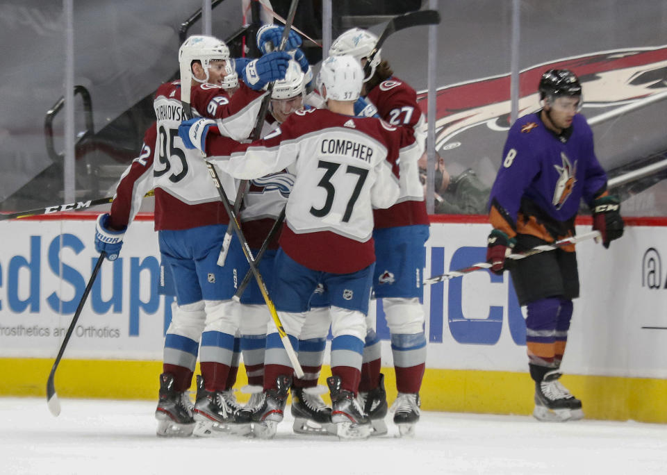 Colorado Avalanche's Andre Burakovsky (95), J.T. Compher (37) and Ryan Graves (27) mob Jacob MacDonald, center, after a goal against the Arizona Coyotes during the second period of an NHL hockey game Saturday, Feb. 27, 2021, in Glendale, Ariz. Coyotes' Nick Schmaltz skates in the background. (AP Photo/Darryl Webb)