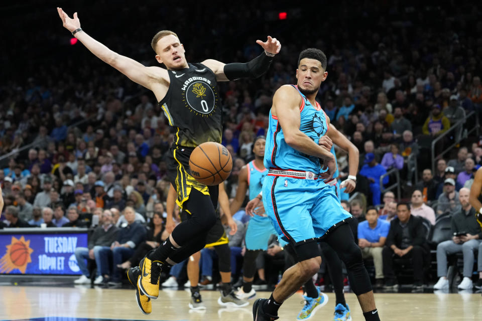 Phoenix Suns guard Devin Booker strips the ball away from Golden State Warriors guard Donte DiVincenzo (0) during the first half of an NBA basketball game, Wednesday, Nov. 16, 2022, in Phoenix. (AP Photo/Matt York)