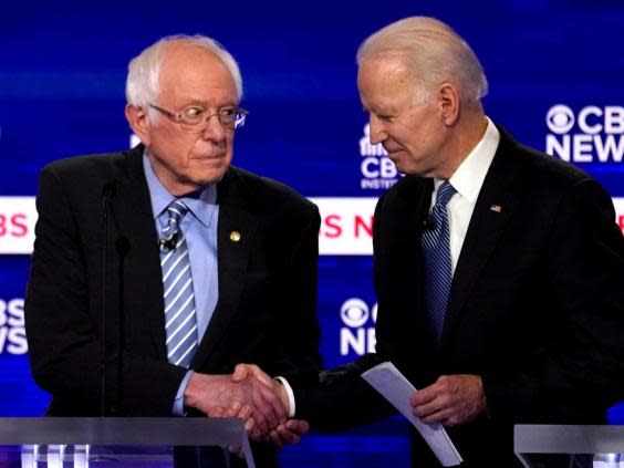 (Vermont Senator Bernie Sanders and former Vice President Joe Biden shake hands at the Democratic presidential debates)