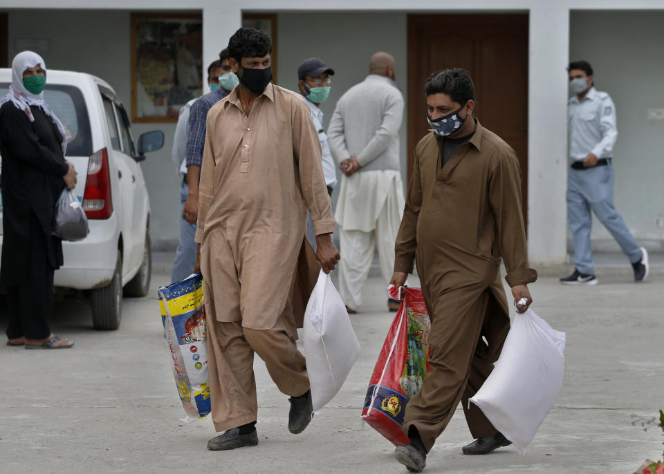 Daily wages workers carry sacks of wheat flour and other food supplies provided for free by a municipally, during a lockdown to try to contain the outbreak of the coronavirus, in Islamabad, Pakistan, Monday, April 6, 2020. (AP Photo/Anjum Naveed)
