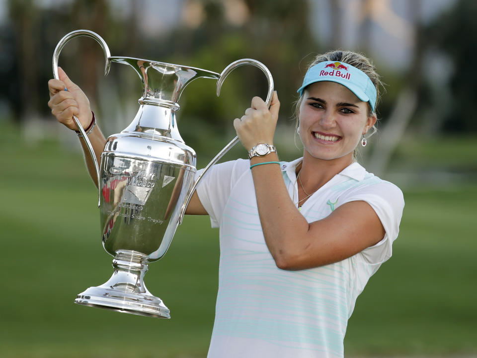 Lexi Thompson holds up the trophy after winning the Kraft Nabisco Championship golf tournament Sunday, April 6, 2014, in Rancho Mirage, Calif. (AP Photo/Chris Carlson)