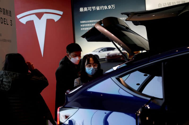FILE PHOTO: Visitors wearing face masks check a China-made Tesla Model Y sport utility vehicle (SUV) at the electric vehicle maker's showroom in Beijing