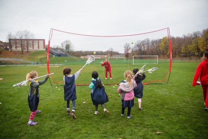 A group of young girls, with the help of some Marist women's lacrosse players, practice shooting and passing a lacrosse ball during the 2022 Pick Up & Play clinic in Highland.