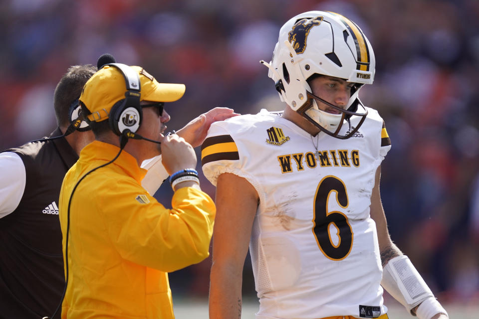 Wyoming running backs coach Gordie Haug, left, talks with quarterback Andrew Peasley during the first half of an NCAA college football game against Illinois Saturday, Aug. 27, 2022, in Champaign, Ill. (AP Photo/Charles Rex Arbogast)