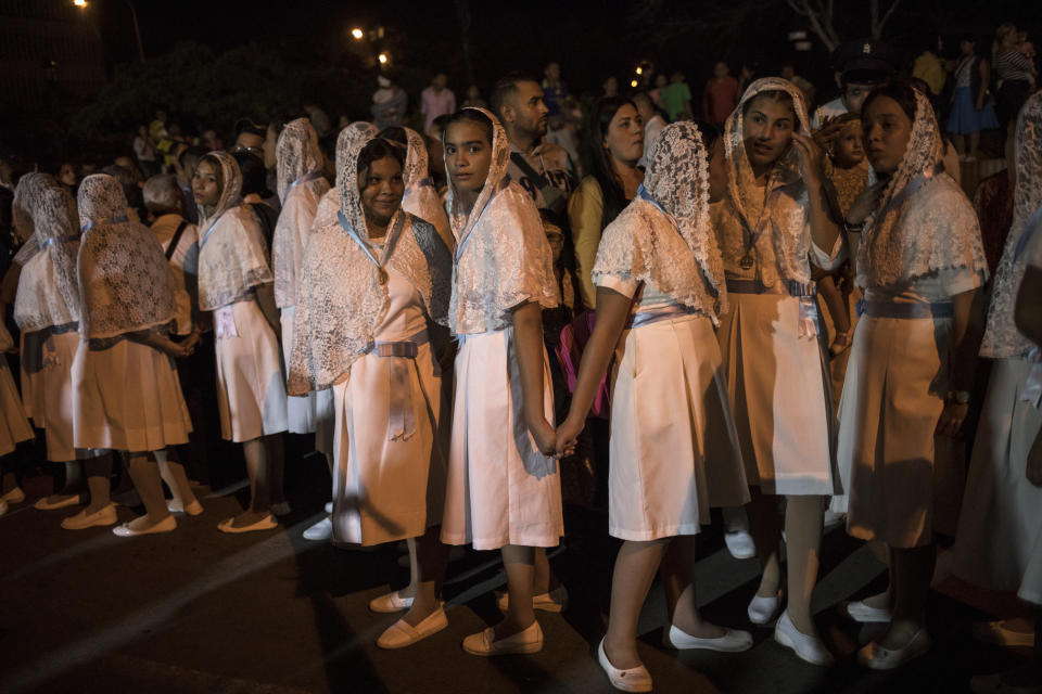 Catholic women hold hands during a procession commemorating the feast day of Our Lady of Chiquinquirá, the patron saint of Zulia state, in downtown Maracaibo, Venezuela, Nov. 18, 2019. Opposition leader Juan Guaidó this year launched a campaign promising to oust President Nicolás Maduro and return the nation to its bygone prosperity. While the power struggle plays out, millions of Venezuelans remain caught in the middle. (AP Photo/Rodrigo Abd)