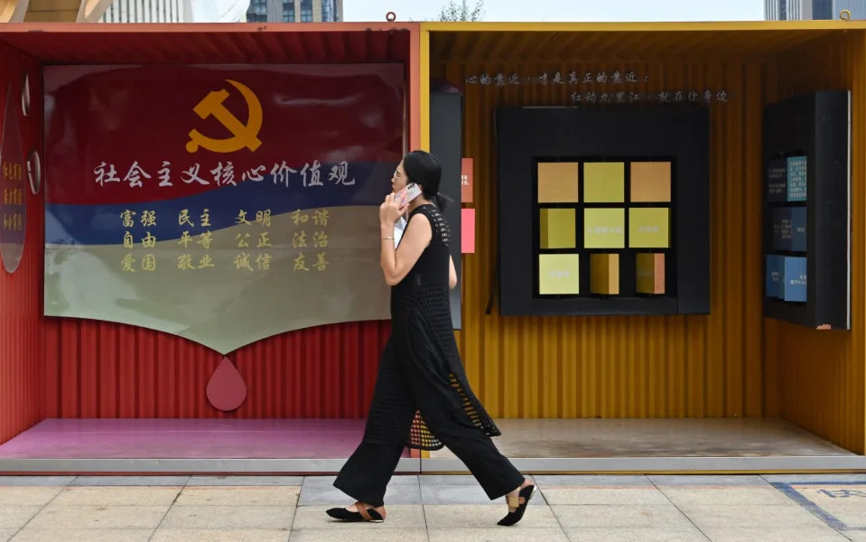 A woman walks past a booth with the Communist Party emblem in Yiwu