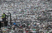 A boat pushes tons of garbage stuck at the foot of the hydro power plant at the Potpecko accumulation lake near Priboj, in southwest Serbia, Friday, Jan. 22, 2021. Serbia and other Balkan nations are virtually drowning in communal waste after decades of neglect and lack of efficient waste-management policies in the countries aspiring to join the European Union. (AP Photo/Darko Vojinovic)