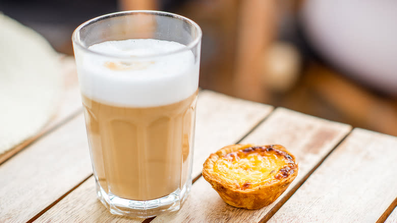 Milky coffee next to egg tart 