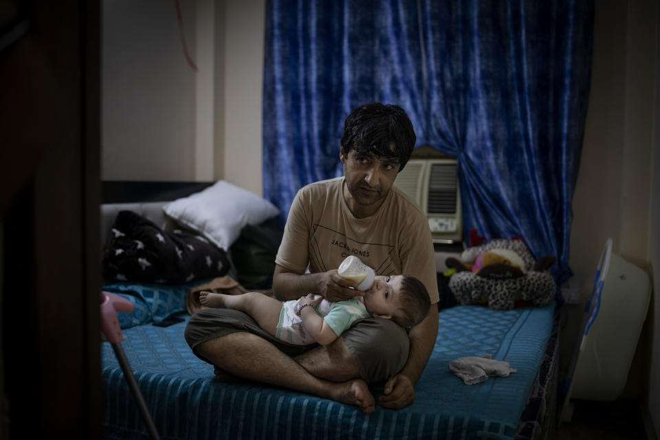 Mohammad Nabi, husband of a former Afghan policewoman Khatera Hashmi, feeds his seven-month-old daughter Bahar inside a rented accommodation in New Delhi, India, on Aug. 13, 2021. When the Taliban shot policewoman Khatira Hashmi and gouged out her eyes, she knew Afghanistan was no longer safe. Along with her husband, she fled to India last year. She was shot multiple times on her way home from work last October in the capital of Ghazni province, south of Kabul. As she slumped over, one of the attackers grabbed her by the hair, pulled a knife and gouged out her eyes. (AP Photo/Altaf Qadri)
