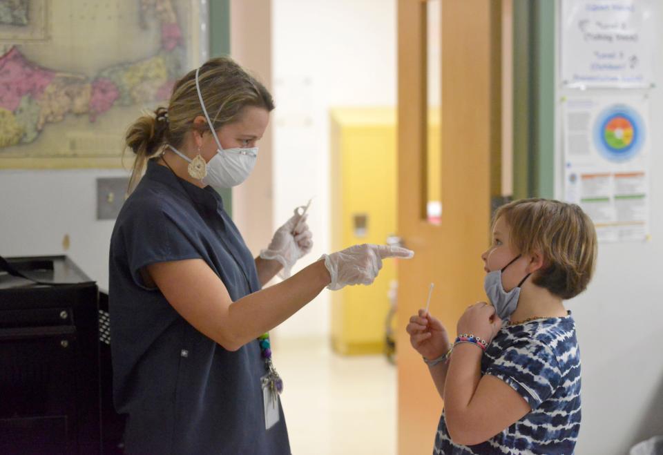 Harwich Elementary School nurse Holly Tavano helps her daughter, Linnea, 10, with a coronavirus test Dec. 6. Students at the school in Massachusetts have access to testing that lets them stay in school if they've had a COVID-19 exposure.