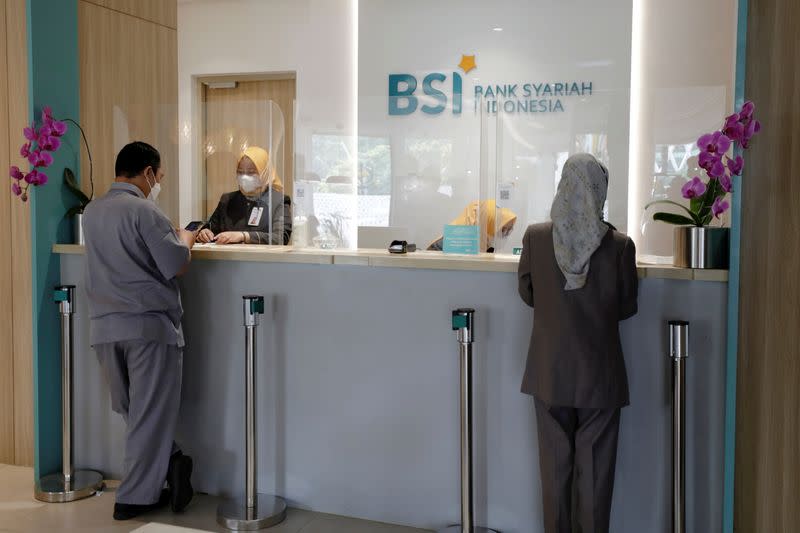 FILE PHOTO: Bank tellers serve customers at Bank Syariah Indonesia in Jakarta