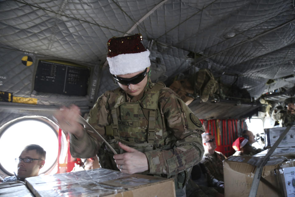 In this Monday, Dec. 23, 2019, photo, a U.S. soldier secures Christmas gifts on a helicopter in Irbil, Iraq bound for American bases in eastern Syria. It's an operation is called Holiday Express - in addition to delivering presents, the U.S.-led coalition forces brought a U.S. military band to play Christmas carols and music to several bases in eastern Syria. (AP Photo/Farid Abdul-Wahid)