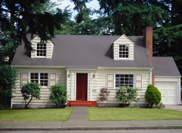 Suburban house with a red door, landscaped front yard, and an attached garage