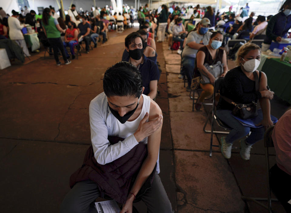 FILE - A youth keeps his hand on the spot where he was vaccinated with Russia's Sputnik V coronavirus vaccine during a vaccination drive at University Stadium in Mexico City, July 23, 2021. On Monday, the U.S. will implement a new air travel policy to allow in foreign citizens who have completed a course of a vaccine approved by the Food and Drug Administration or the World Health Organization. That leaves people in Mexico, Hungary, Russia and elsewhere who received the non-approved Russian Sputnik V vaccine or the China-produced CanSino vaccine ineligible to board U.S.-bound flights. (AP Photo/Fernando Llano, File)