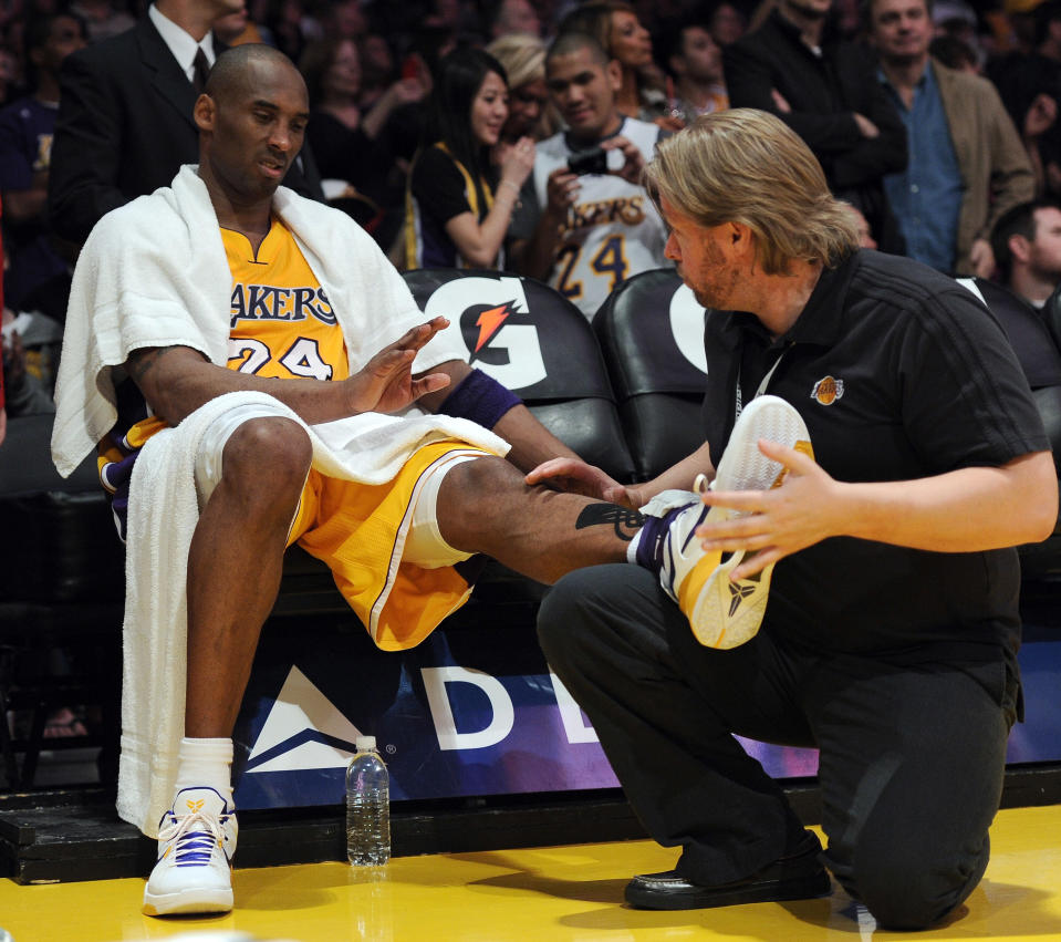 Lakers guard Kobe Bryant receives help from a trainer during a timeout in a game against the Houston Rockets on April 6 in Los Angeles. (Photo by Harry How/Getty Images)