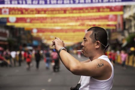 A Chinese tourist with a tattoo of China's late Chairman Mao Zedong takes pictures in Bangkok's Chinatown decorated for the Chinese Lunar New Year February 19, 2015. REUTERS/Damir Sagolj/Files