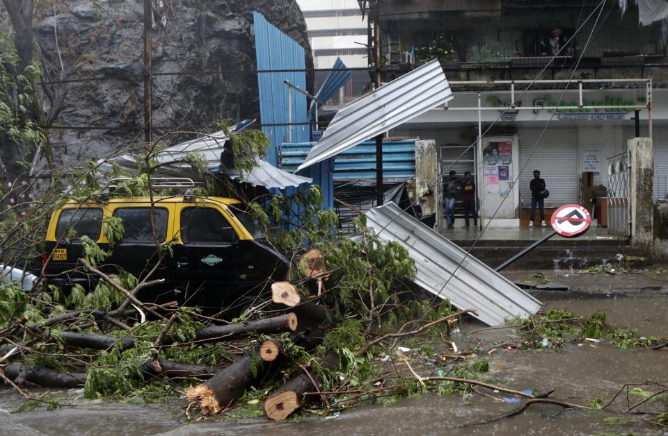 A taxi car that was damaged after a tree fell on it during a heavy rain in Mumbai, India, Monday, May 17, 2021. Cyclone Tauktae, roaring in the Arabian Sea was moving toward India's western coast on Monday as authorities tried to evacuate hundreds of thousands of people and suspended COVID-19 vaccinations in one state. (AP Photo/Rajanish Kakade)