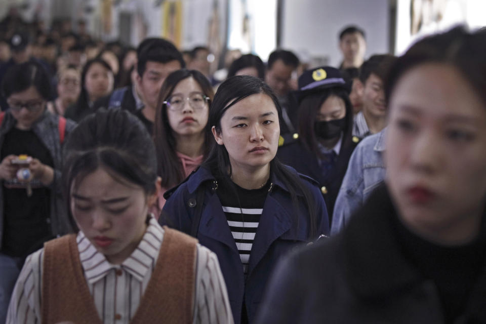 In this Wednesday, April 17, 2019, photo, Young Chinese people walk inside a subway station during the evening rush hour in Beijing. Remarks by the head of Chinese online business giant Alibaba, Ma Jack, one of China's richest men, that young people should work 12-hour days, six days a week if they want financial success have prompted a public debate over work-life balance in the country. (AP Photo/Andy Wong)