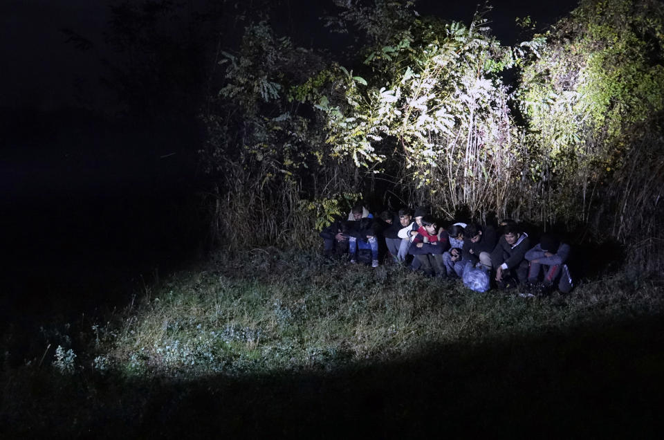 In this photo taken Saturday, Nov. 9, 2019, Bosnian border police officers guard migrants after making the illegal crossing from Serbia by the Drina river, the natural border between Bosnia and Serbia, near eastern Bosnian town of Zvornik, Bosnia. Bosnian border police are warning they cannot contain migratory pressures along the country's eastern border with Serbia, warning the situation could easily escalate and put in danger the overall stability of their politically fragile nation. (AP Photo/Eldar Emric)