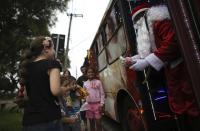 Bus driver Edilson, 45, also known as "Fumassa", greets children as he wears a Santa Claus outfit inside an urban bus decorated with Christmas motives in Santo Andre, outskirts of Sao Paulo December 10, 2013. Fumassa dresses as Santa Claus every year while driving his bus. Picture taken December 10. REUTERS/Nacho Doce (BRAZIL - Tags: SOCIETY TRANSPORT)