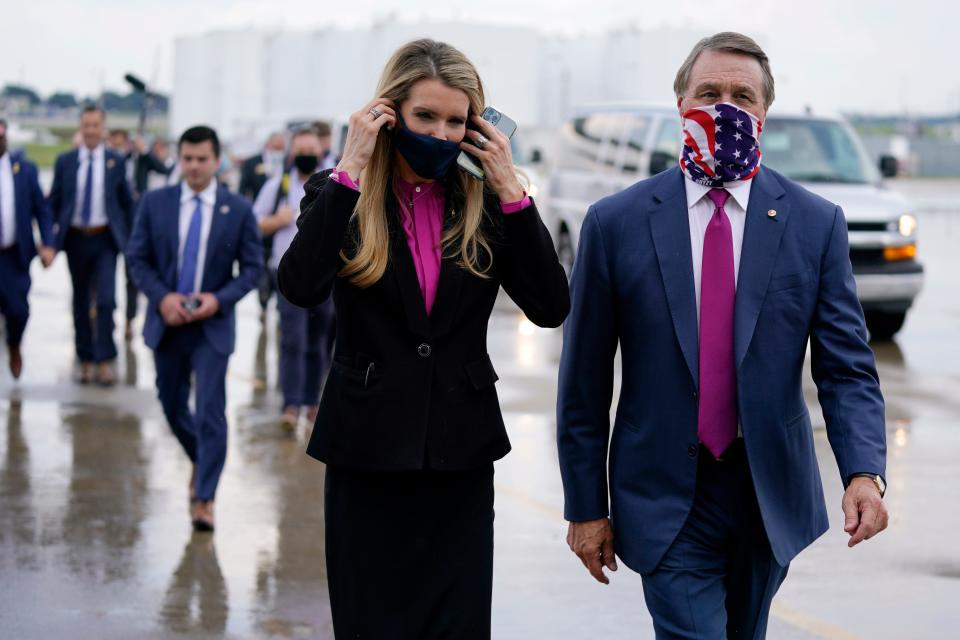 In this July 15 file photo Sen. Kelly Loeffler, R-Ga., puts on a face mask as she walks with Sen. David Perdue, R-Ga., right, at UPS Hapeville Airport Hub in Atlanta. 