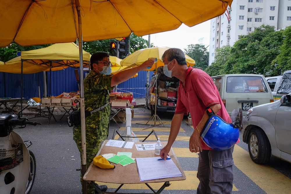 A People’s Volunteer Corps (Rela) member checks the temperature of people at the entrance of the Taman Desa Phase 1 night market in Kuala Lumpur February 5, 2021. — Picture by Yusof Mat Isa