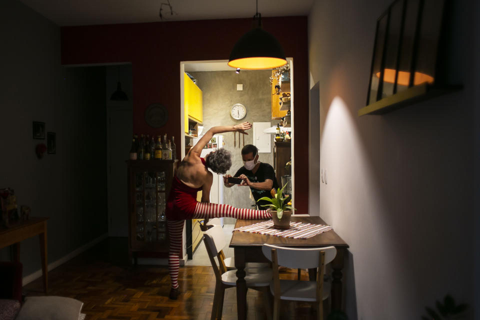 Regina Oliveira performs as her partner Paulo Ricardo records on a cell phone for live, online streaming of the "Benditas Genis" women's clown festival at her home during the COVID-19 pandemic in Rio de Janeiro, Brazil, Sunday, March 14, 2021. “I perceive that, as time passes, the public is tiring of such a virtual relationship," said the clown and trapezist member of Theater of the Anonymous. (AP Photo/Bruna Prado)