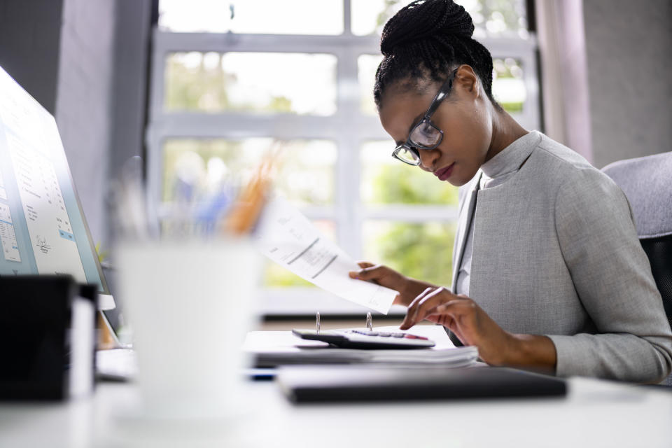 Woman typing on a calculator from home