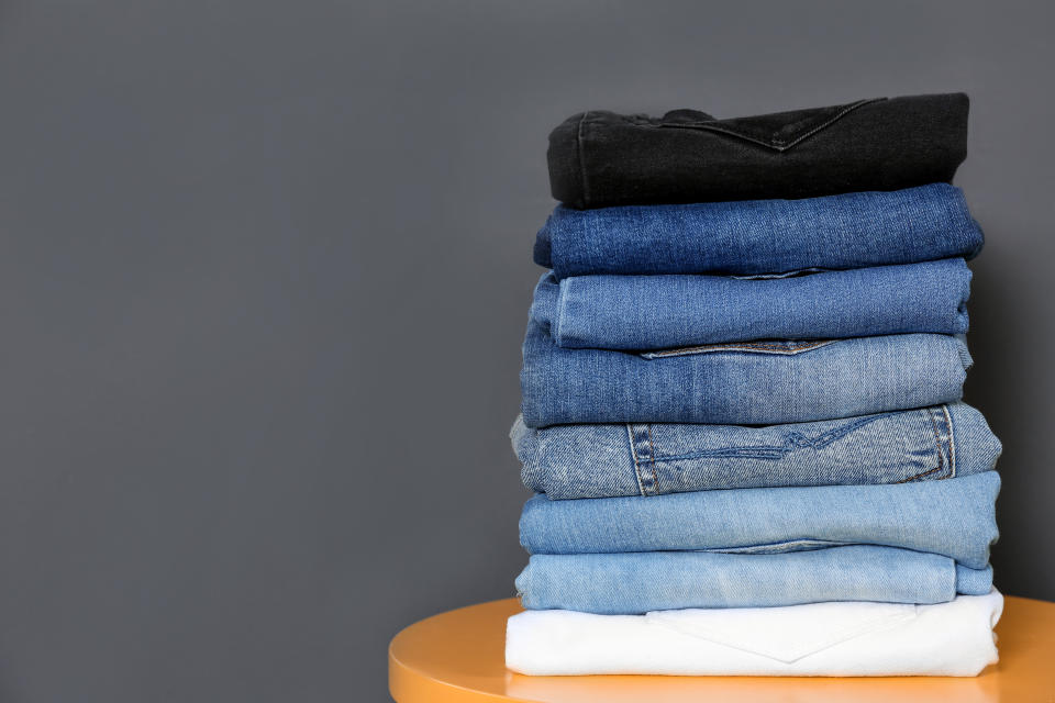 Stack of different jeans on  table against gray background. Space for text